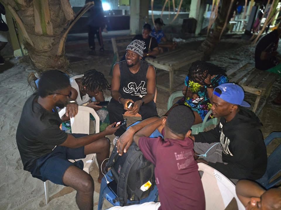 Campers gathered in a circle on the sand after dark