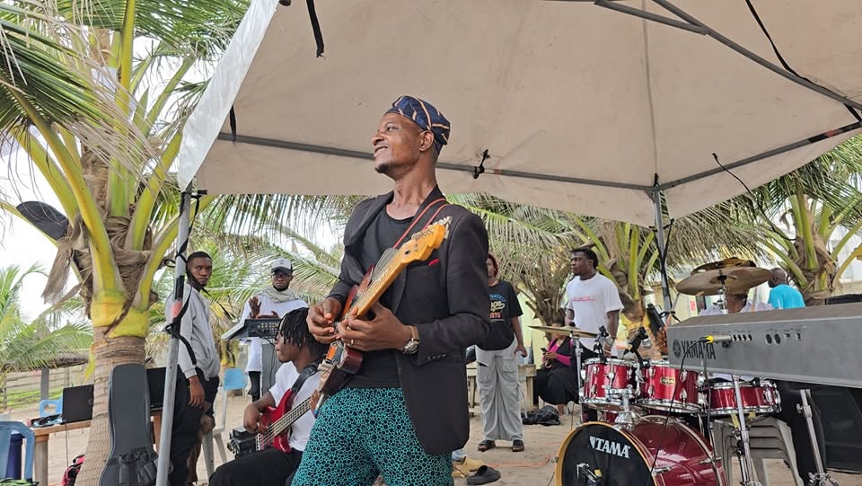 A guitarist performing under the beach canopy with the camp band